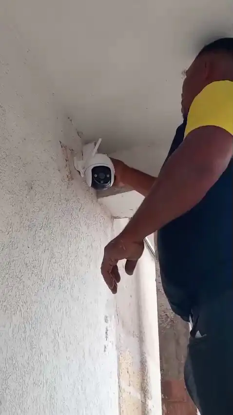 Técnico da GMTEL instalando câmera no alto da parede