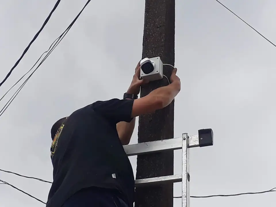 Técnico fixando câmera em poste