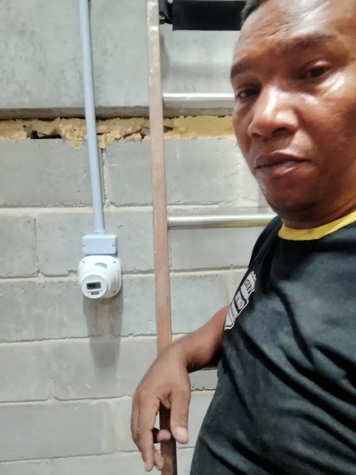 Técnico ao lado de câmera instalada em parede de bloco