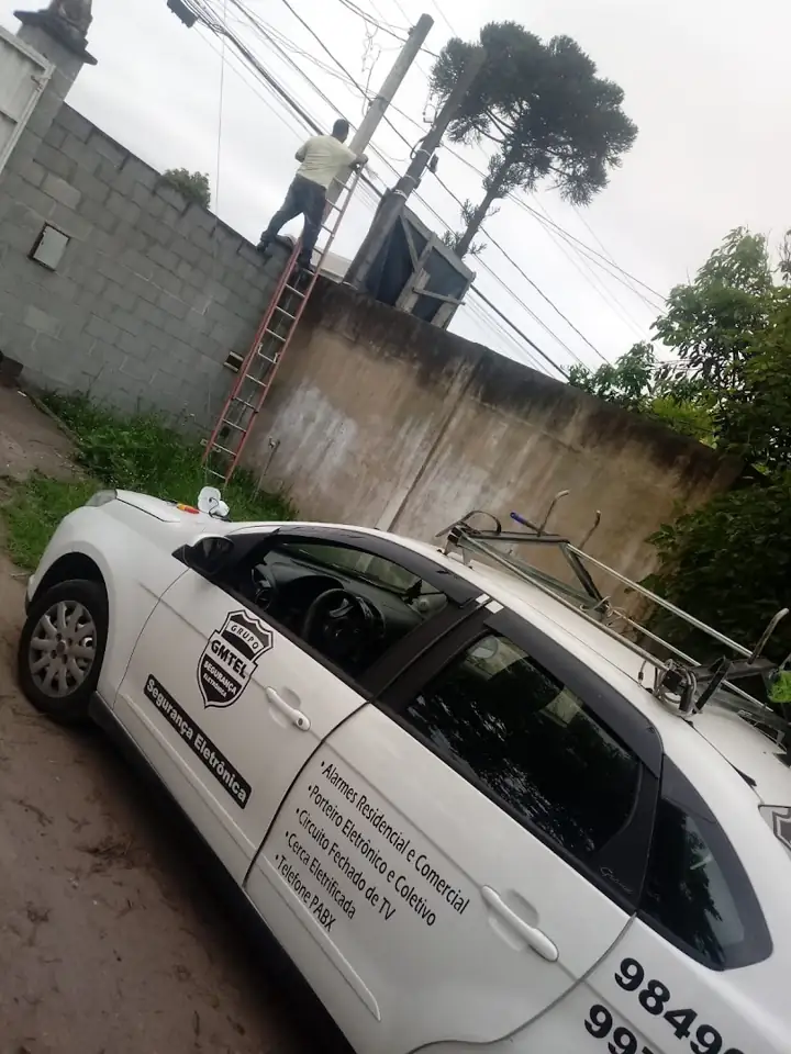 Carro da GMTEL estacionado em rua com muro ao fundo